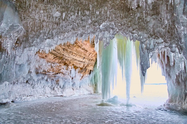 Ice crystals hanging from small cave with view of lake and icicles