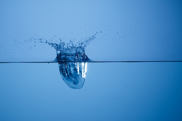 Ice cube thrown into water container and photographed at high speed