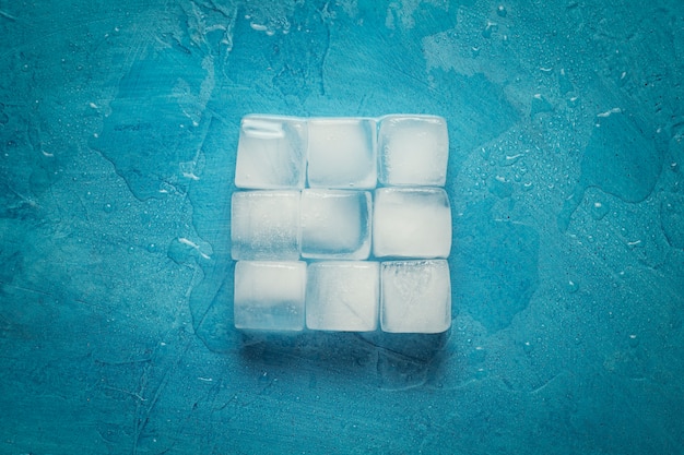 Cubetti di ghiaccio su uno sfondo di pietra blu. forma del quadrato concetto di produzione di ghiaccio. vista piana, vista dall'alto