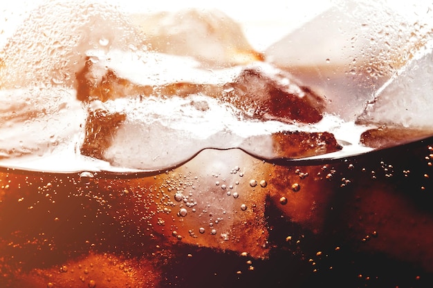 Ice cubes in cola beverage close up illuminated from inside