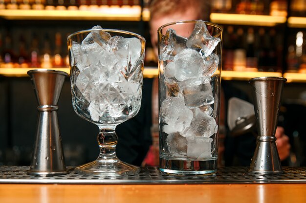 Ice cubes in an empty glass on a bar counter.