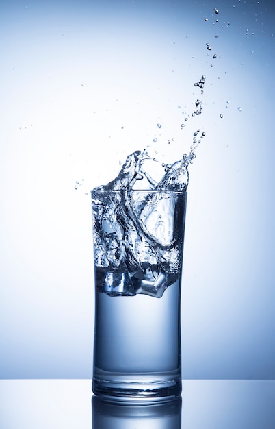 Photo ice cubes falling in a glass of water with splash