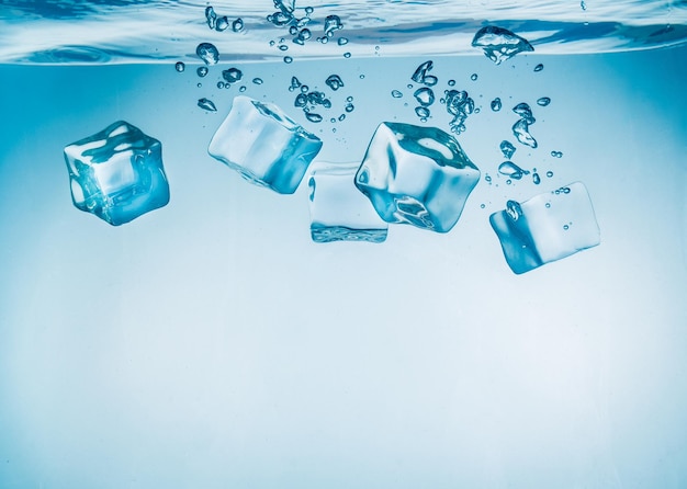 Ice cubes falling into the water sinking to the bottom. Abstract background.