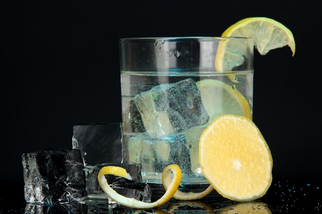 Ice cubes in glass with lemon on dark blue background