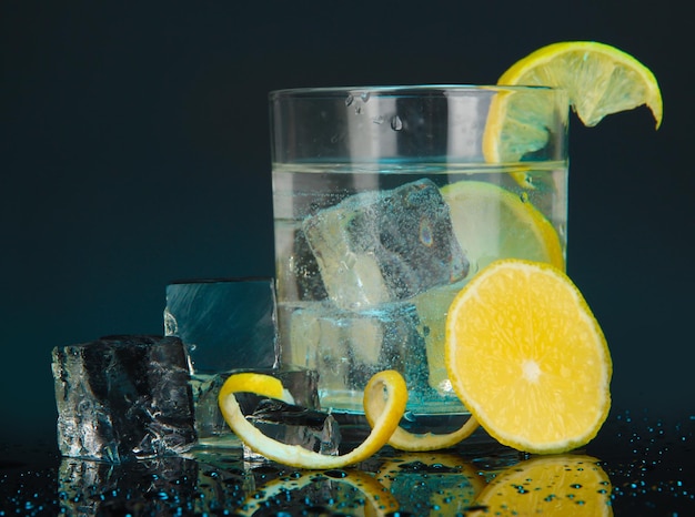 Ice cubes in glass with lemon on dark blue background