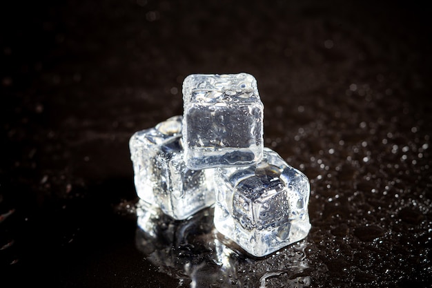 Ice cubes reflection on black table background.