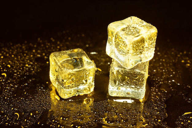 Кубики льда на отражениях желтого света.