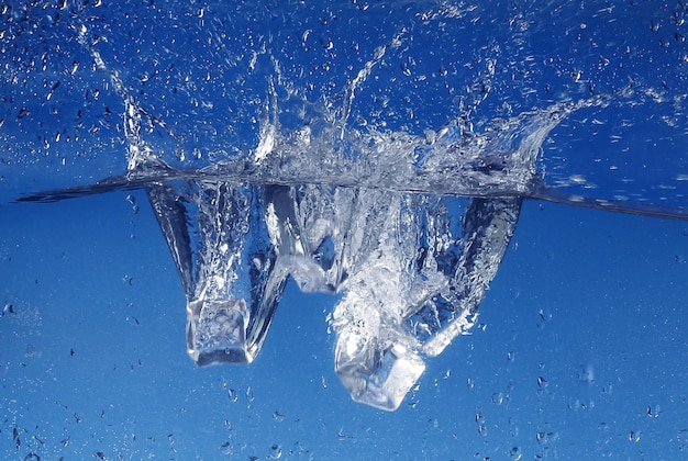 Ice cubes splashing into water, close-up