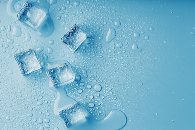 青いテーブル、上面図に溶けた水の滴と角氷。蒸し暑い中の鮮度。冷たい飲み物
