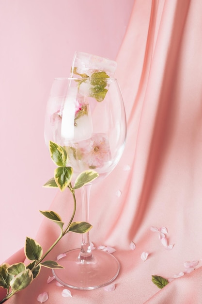 사진 꽃 이 녹고 있는 얼음 큐브 가 뒷면 에 있는 실키 핑크색 천 에 있는 음료 에 녹고 있다