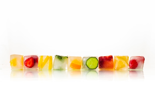 Кубики льда с фруктами на ярком белом фоне. Концепция жаркого лета, десерт, мороженое. Плоская планировка, вид сверху