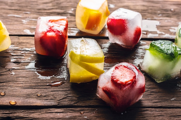 Ice cubes with fruit on wooden table. Hot summer concept, dessert