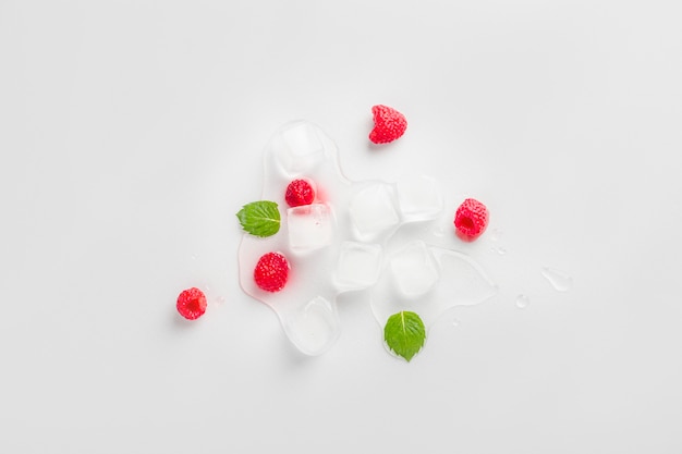 Ice cubes with raspberries and mint leaf on wooden table. Homemade skincare hydrating ice cubes