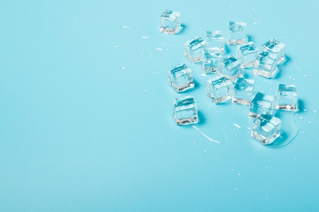 Ice cubes with water on a blue background. Ice concept for drinks.