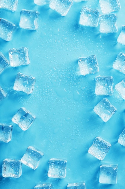 Ice cubes with water drops scattered on a blue background top view