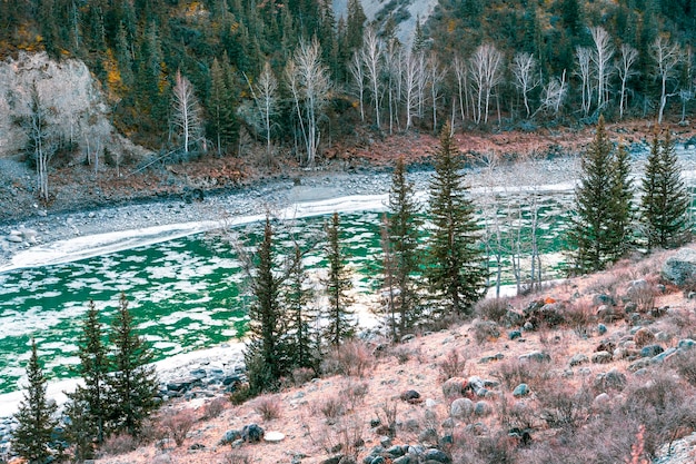 山の川の氷の漂流。初冬の夕方に湖につながる小さな川