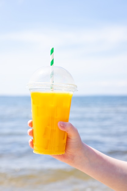 Ледяной напиток сок желтый лимонад на пляже море побережье берег апельсин свежий освежающий напиток расслабиться