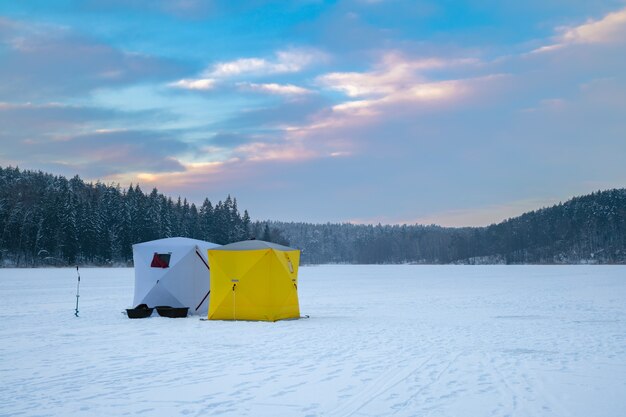 Ice fishing tent on a frozen lake at sunset