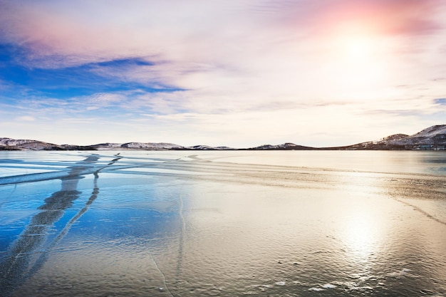 Лед на замерзшем озере на закате. Красивый зимний пейзаж