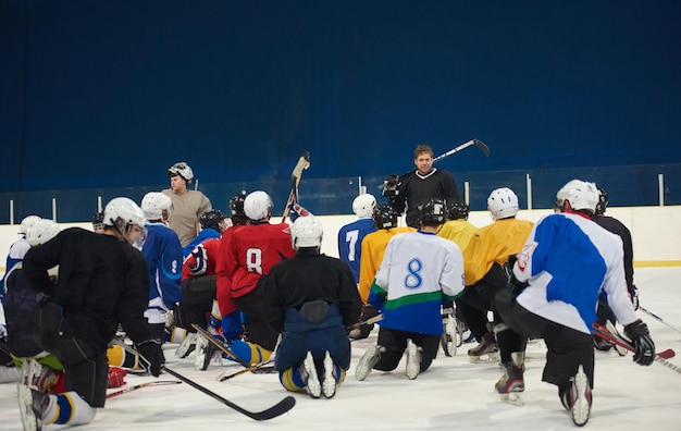 Photo ice hockey players team group meeting with trainer  in sport arena indoors