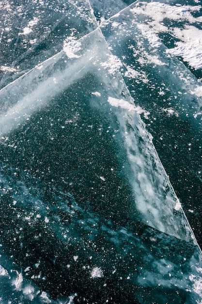 バイカル湖の氷は深いひび割れのある雪で粉にされた厚いひび割れた氷垂直方向