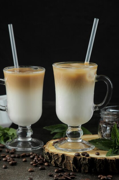 Ледяной латте или ледяной кофе с молоком и кубиками льда в стеклянном стакане на темном фоне. освежающий напиток. летний напиток.