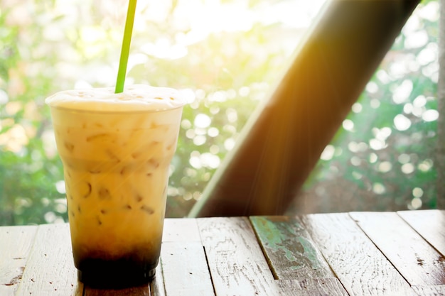 Photo ice latte on a wooden terrace by the garden with sun flare