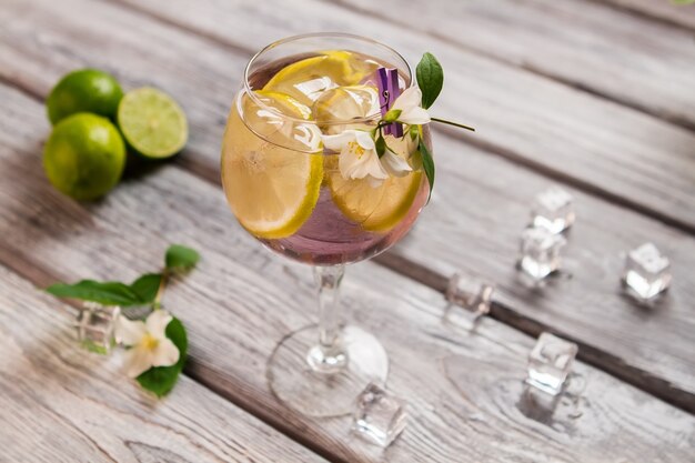 Лед и лимон внутри напитка. Нарезанный фрукт и маленький цветок. Том Коллинз с дорогим джином. Сок смешать с холодной водой.
