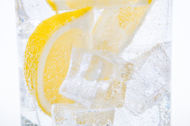 Ghiaccio, fette di limone e acqua limpida in un bicchiere.