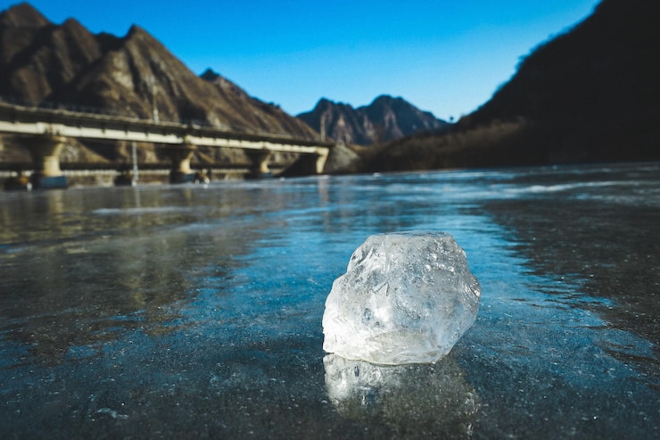 Photo an ice lies still on a frozen lake with a train track bridge in the distance