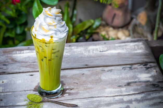 Foto tè verde del ghiaccio matcha con panna montata sulla tavola di legno