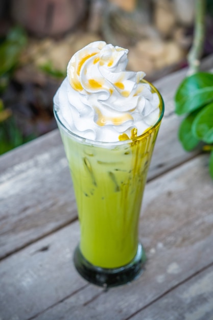 Ice Matcha green tea with whipped cream on wooden table