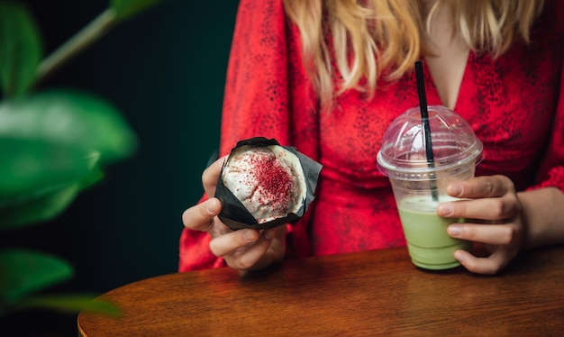 Primo piano di ghiaccio matcha latte e cupcake in un caffè in mani femminili