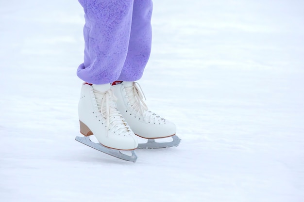 Foto gambe di donna pattinaggio su ghiaccio sulla pista di pattinaggio. hobby e sport invernali