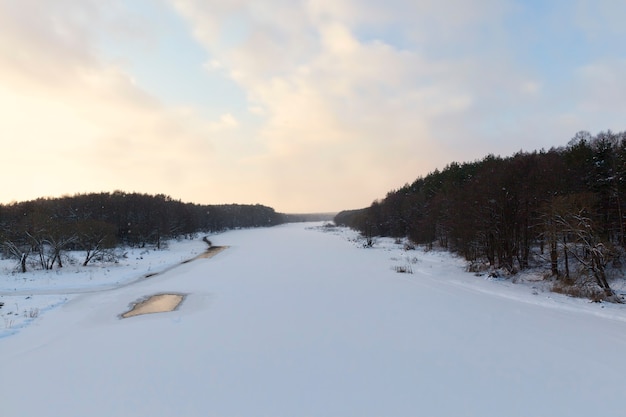 日没時の氷と雪に覆われた川の表面、冬季に凍結