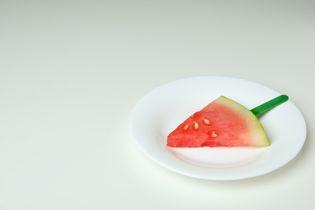 Ice stick with watermelon slice on plate on white background