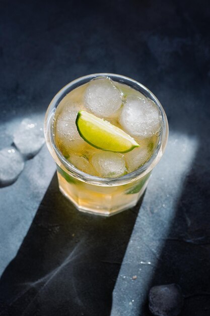 Photo ice tea with ice cubes lime mint leaves in the glass on gray stone background