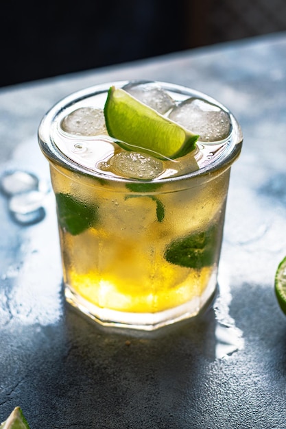 Ice tea with ice cubes lime mint leaves in the glass on gray stone background