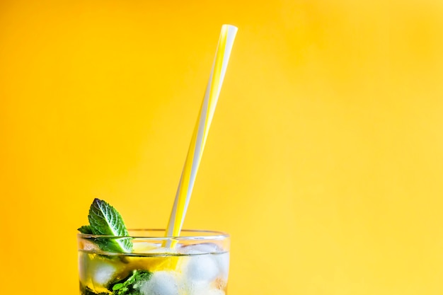 Ice tea with ice, lemon and mint on a combined colored yellow background