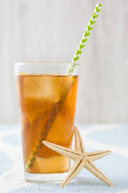 Ice tea with lemon on a beach towel