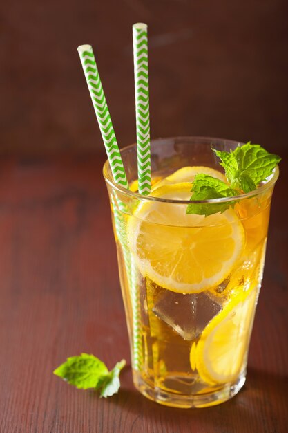 Ice tea with lemon and mint on dark rustic background