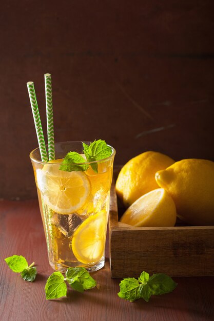 Ice tea with lemon and mint on dark rustic background