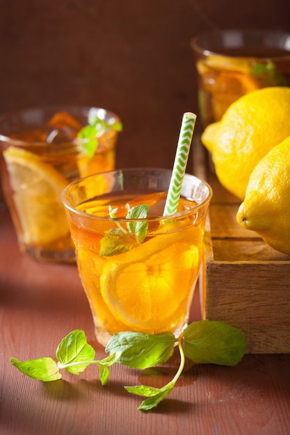 Ice tea with lemon and mint on dark rustic background