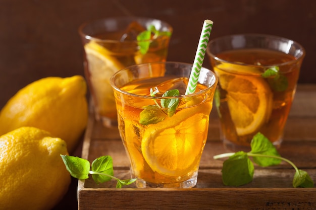 Ice tea with lemon and mint on dark rustic background