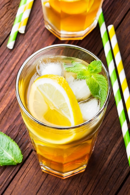 Ice tea with lemon and mint on a wooden background