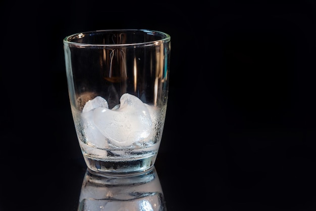 Ice in whisky glass on a black table