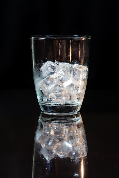 Ice in whisky glass on a black table