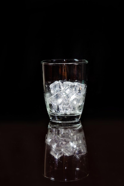 Ice in whisky glass on a black table