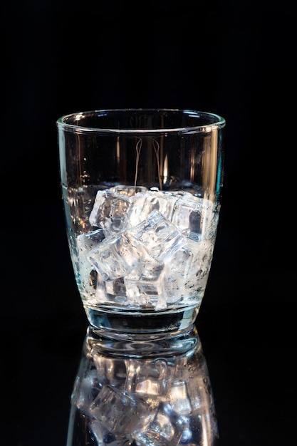 Ice in whisky glass on a black table