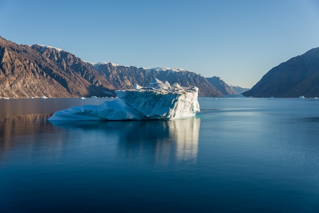 穏やかな水の反射とグリーンランドフィヨルドの氷山。日当たりの良い天気。ゴールデンアワー。